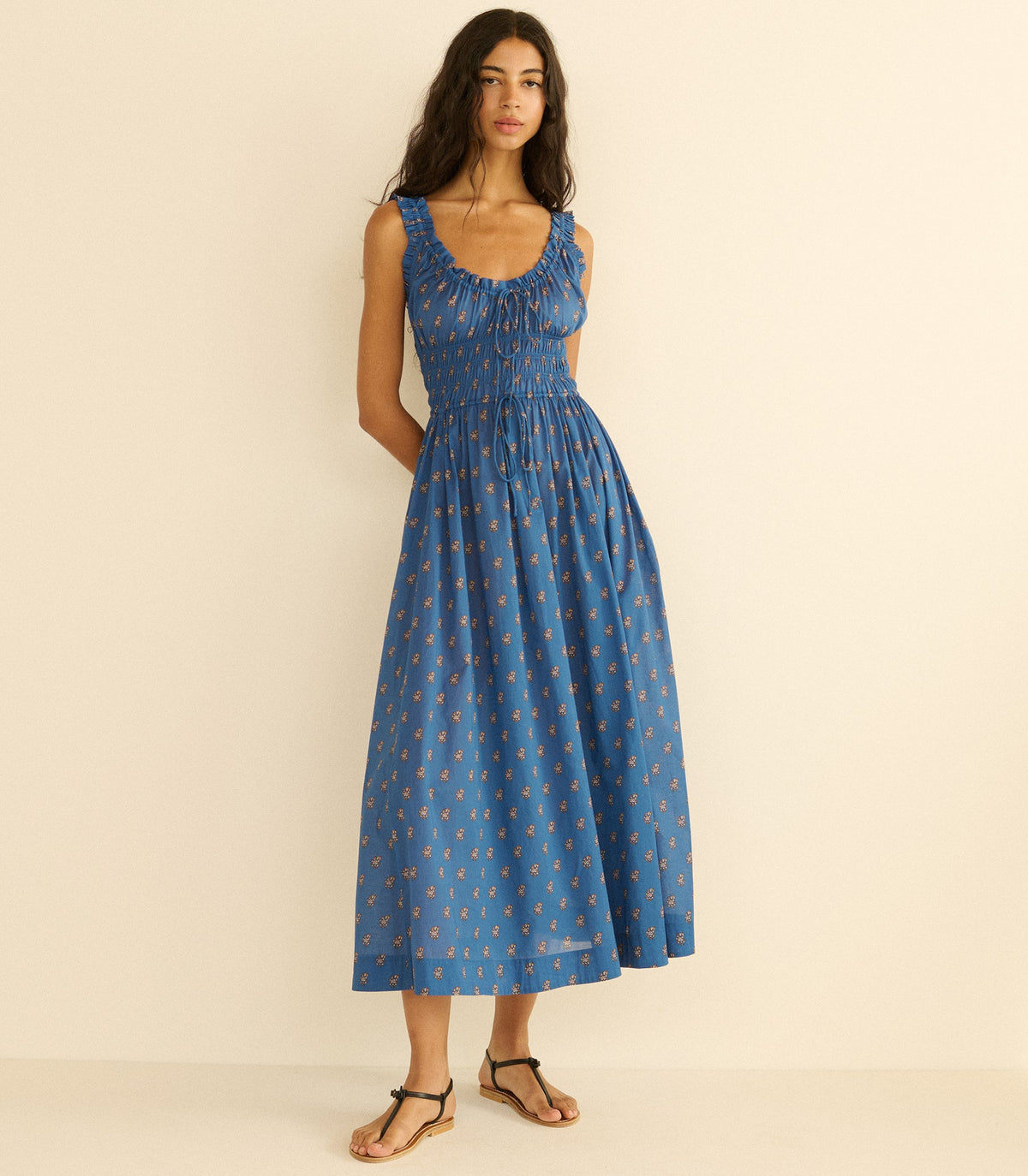 Woman wearing a blue paisley dress with a pattern on a beige background